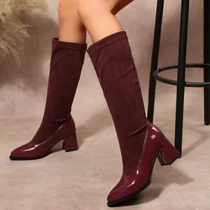 Close-up of burgundy block heel boots with pointy toe and mixed patent suede textures.