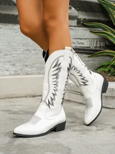 Detailed view of white Western boots with black embroidery and pointed toe
