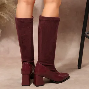 Close-up of burgundy chunky heel boots with elegant patent leather and suede patchwork