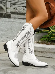 Close-up of white western tall boots with intricate black embroidery and block heel