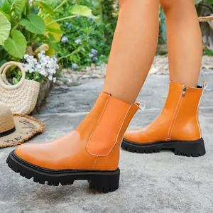 Gros plan de bottines à plateforme orange vif avec fermeture éclair latérale et semelles épaisses