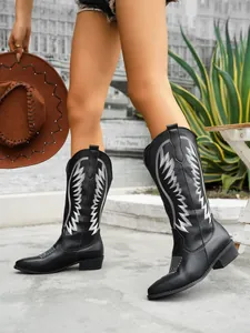 Side detail of black western tall boots featuring white embroidery and block heels