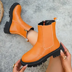 Détail rapproché de bottines Chelsea en cuir orange vif avec semelles compensées noires