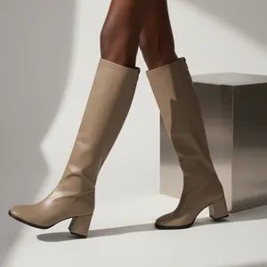 Detailed shot of elegant beige knee-high boots with square toe and chunky block heel