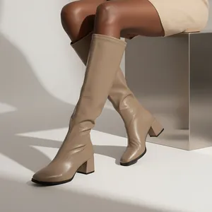 Close-up of elegant beige square toe knee-high boots with a stable chunky block heel