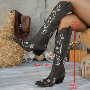 Macro view of dark brown cowboy boots with white floral embroidery and heel height details