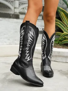 Close-up detail of stylish black Western tall boots featuring white embroidery and pointed toe