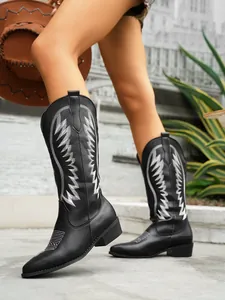 Detailed view of black Western boots featuring elegant white embroidery and pointed toe