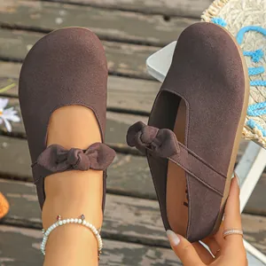 Close-up of brown suede Mary Jane mules with bow strap and platform sole