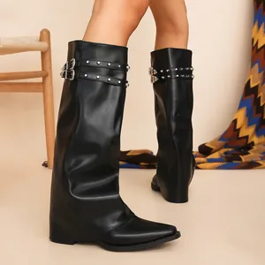 Dettaglio di stivali gaiter neri con borchie, fibbie retrò e altezza ginocchio.