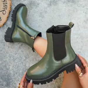 Gros plan de bottines Chelsea vert olive élégantes avec semelles épaisses et détails zippés.