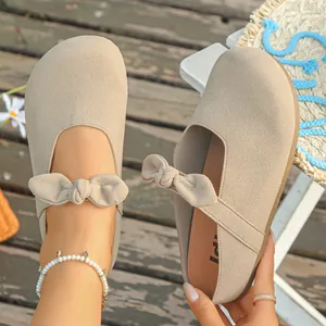 Close-up detail of stylish beige suede mules featuring a charming bow knot design