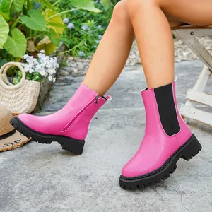 Gros plan de bottines à plateforme roses vives avec fermeture éclair portées par un mannequin.
