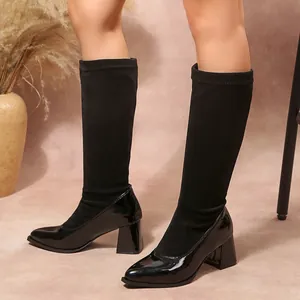 Close-up of black pointed toe block heel boots with suede and patent leather patchwork.