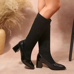 Close-up detail of black block heel boots featuring patent leather and suede patchwork design