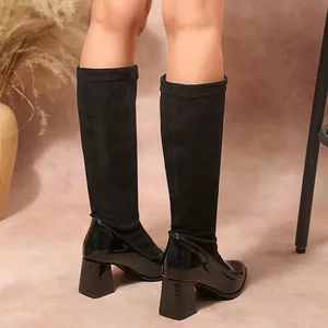 Rear view of black block heel boots featuring suede and patent leather patchwork design