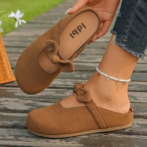Stylish brown platform Birkenstock style mule sandals with bow detail in sunny outdoors