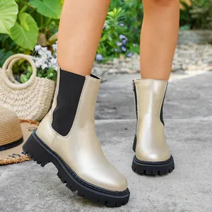 Gros plan de bottines dorées métallisées avec semelles épaisses noires et fermetures éclair.