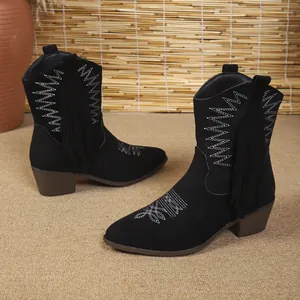 Close-up of black western ankle boots with white embroidery, tassels and chunky brown heels.
