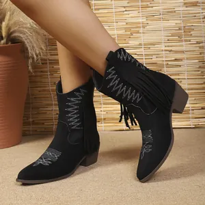 Detail shot of black suede western boots with white floral embroidery and fringe