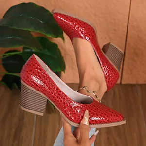 A macro detail view of red crocodile pattern pointed toe pumps with chunky heels