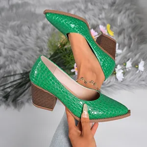 Close-up of green crocodile embossed chunky heel pumps featuring a pointed toe design.