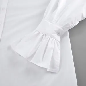 Macro detail shot of the elegant ruffled flared cuff on a white long sleeve shirt