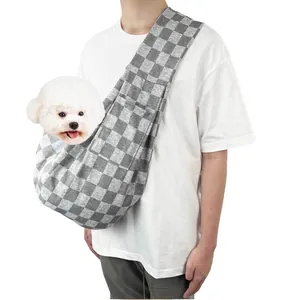 Grey checkered pet sling carrier bag for small dogs and cats shown in use by a model