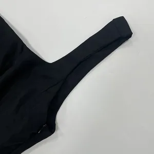 Close-up view of a black square neck dress showing side zipper and strap detail.