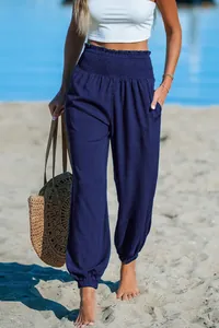 Detail view of navy blue loose beach pants with a smocked high waist and cuffed ankles