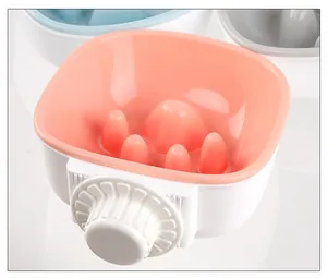 Vue macro détaillée d'une gamelle anti-glouton suspendue pour cage d'animaux rose.