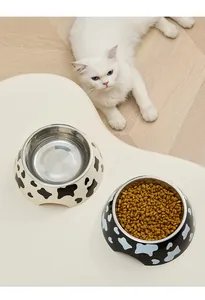 Macro view of stainless steel pet bowls with cow print, one filled with dry cat food.