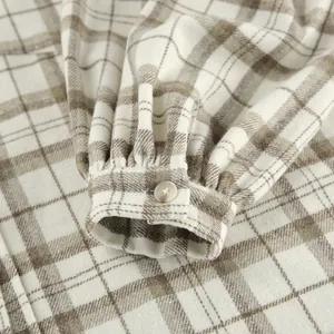 Close-up detail of a vintage plaid shirt sleeve cuff showing fabric texture and button