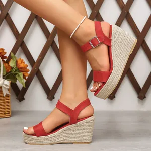 Détail de sandales compensées en daim rouge avec talons en jute tressé et bride