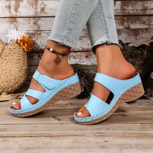 Sandalias con plataforma de cuña azul claro para mujer sobre un suelo de madera.