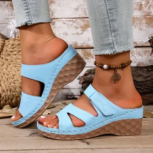 Detalle de sandalias de cuña azul claro con diseño calado y suela de plataforma con textura.