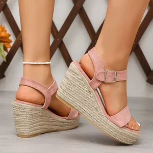 Détail de sandales compensées en daim rose avec talon en corde et bride cheville