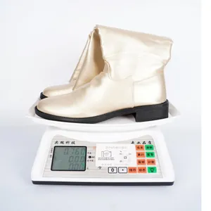 Detailansicht goldener Kniestiefel im britischen Stil mit Gewichtsangabe auf Waage