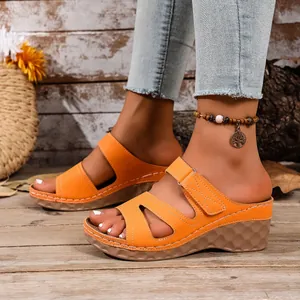 Vista detallada de elegantes sandalias de cuña naranja con tiras decorativas caladas