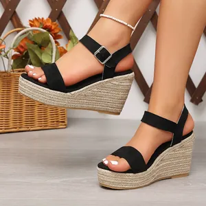 Détail de sandales compensées en daim noir avec plateforme en corde tressée chic