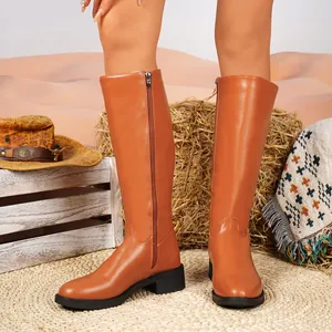 Braune kniehohe Stiefel im britischen Stil, präsentiert von einem Model im Freien.