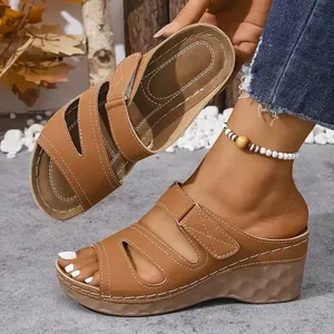 Primer plano de elegantes sandalias de cuña marrones para mujer con tiras huecas