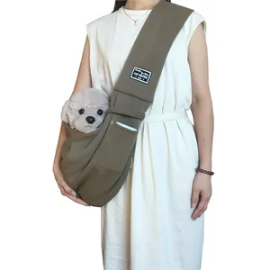 Close-up of a person wearing a brown pet sling carrier with a small dog inside