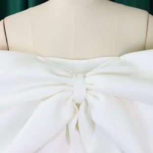 Dettaglio di un elegante top a fascia bianco con spalle scoperte e grande fiocco decorativo