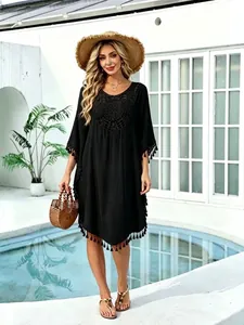 Elegant black beach cover-up featuring crochet details and tassel trim poolside