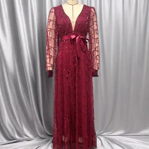 Detailed view of burgundy mesh sequin evening gown featuring V-neck and long sleeves