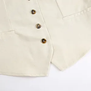 Close-up of khaki linen vest featuring tortoiseshell buttons and natural fabric texture.