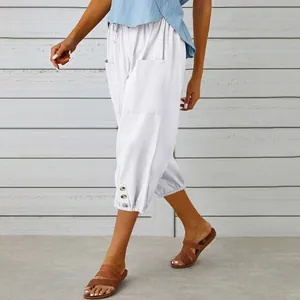Detail of white cotton linen cropped pants featuring hem buttons and side pockets
