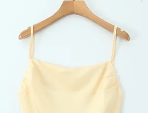 Detail view of a pale yellow summer dress with thin straps and ruched neckline