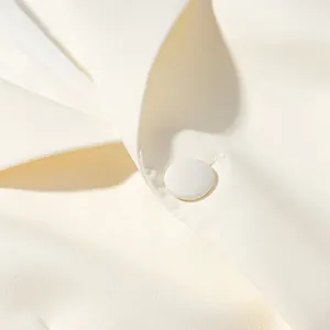 Macro view of high-quality fabric-covered button and lapel detail on a white blazer